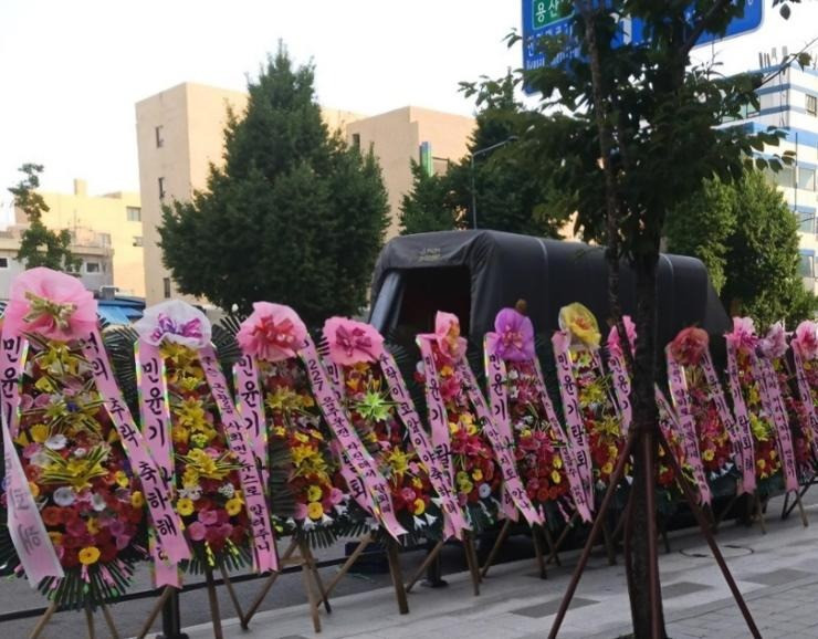 Fan gửi nhiều vòng hoa chứa thông điệp kêu gọi Suga rời khỏi BTS trước cổng trụ sở Hybe. Ảnh: X. Fan gửi nhiều vòng hoa chứa thông điệp kêu gọi Suga rời khỏi BTS trước cổng trụ sở Hybe. Ảnh: X.