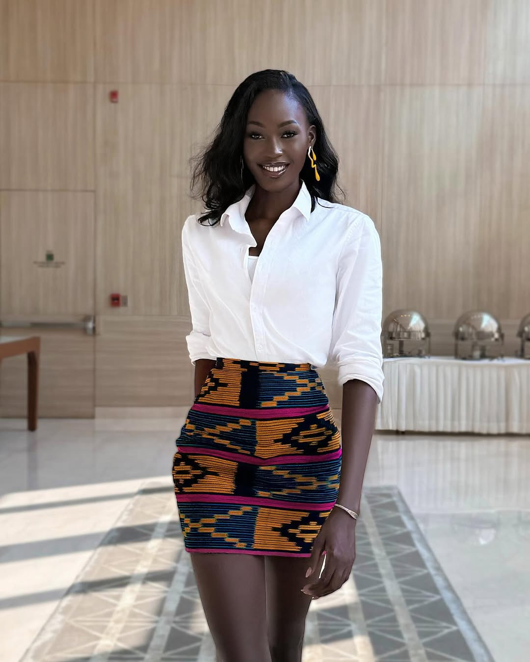 Fatoumata Coulibaly khéo léo sử dụng chân váy có họa tiết đặc trưng của quê hương mình, kết hợp cùng áo sơ-mi trắng, mang lại vẻ hiện đại, độc đáo. Trang phục làm nổi bật đôi chân dài, thẳng tắp của Fatoumata Coulibaly.