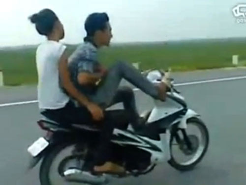 Nam thanh niên coi thường tính mạng, lái xe bằng một chân chở bạn gái phóng như bay. Ảnh: Chụp từ clip