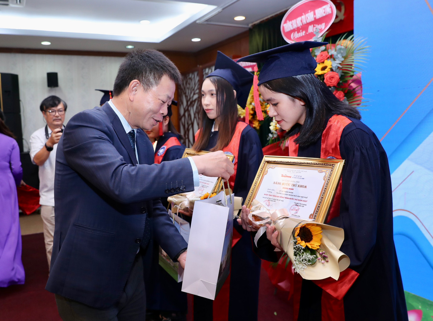 Nhà báo Phùng Công Sưởng - Phó tổng biên tập Báo Tiền Phong và Anh Nguyễn Hải Nam, Phó Chánh văn phòng Trung ương Đoàn trao hoa, học bổng quà của Văn phòng Chính phủ cho sinh viên.