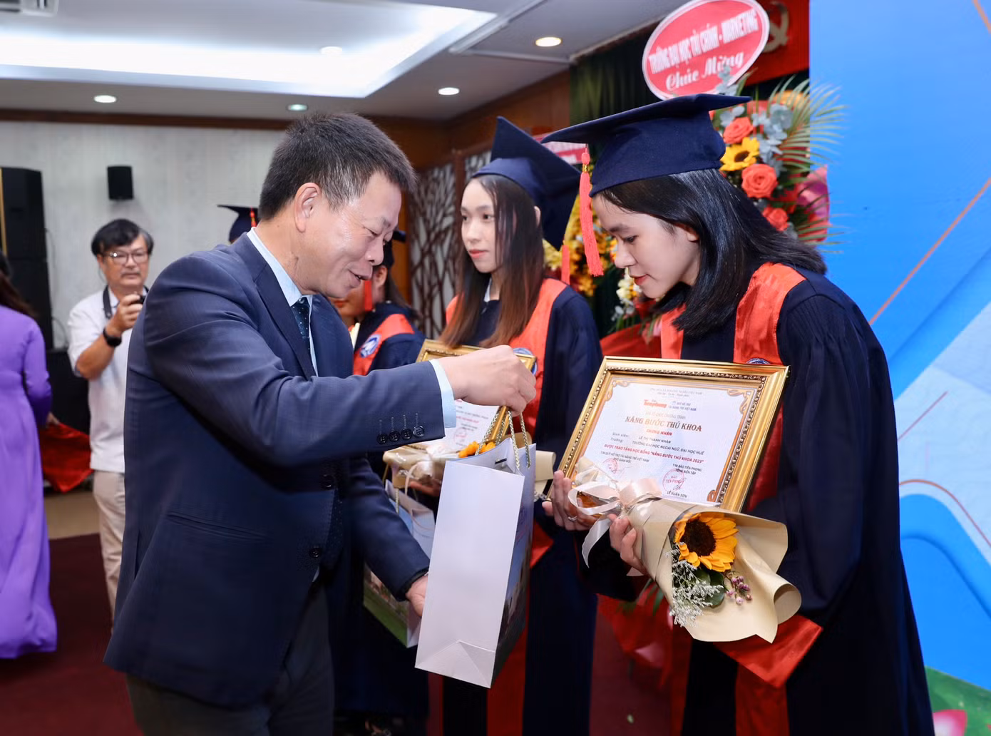 Nhà báo Phùng Công Sưởng - Phó tổng biên tập Báo Tiền Phong và Anh Nguyễn Hải Nam, Phó Chánh văn phòng Trung ương Đoàn trao hoa, học bổng quà của Văn phòng Chính phủ cho sinh viên.