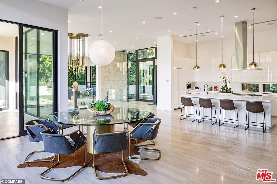 Khu vực bếp có tông màu chủ đạo là trắng, có cả quầy bar để ăn sáng và bàn tròn cho những bữa còn lại và tiếp khách.