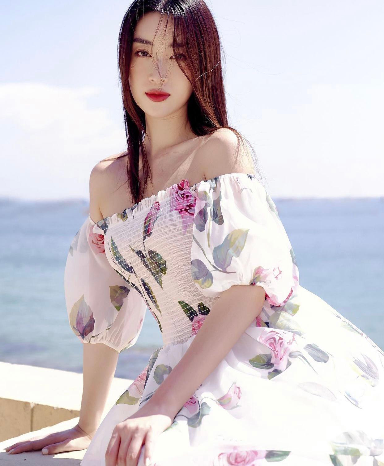 Hoa hậu Đỗ Mỹ Linh khoe nhan sắc dịu dàng nhưng không kém phần quyến rũ khi diện bộ váy hoa trễ nải vai trần trên biển.