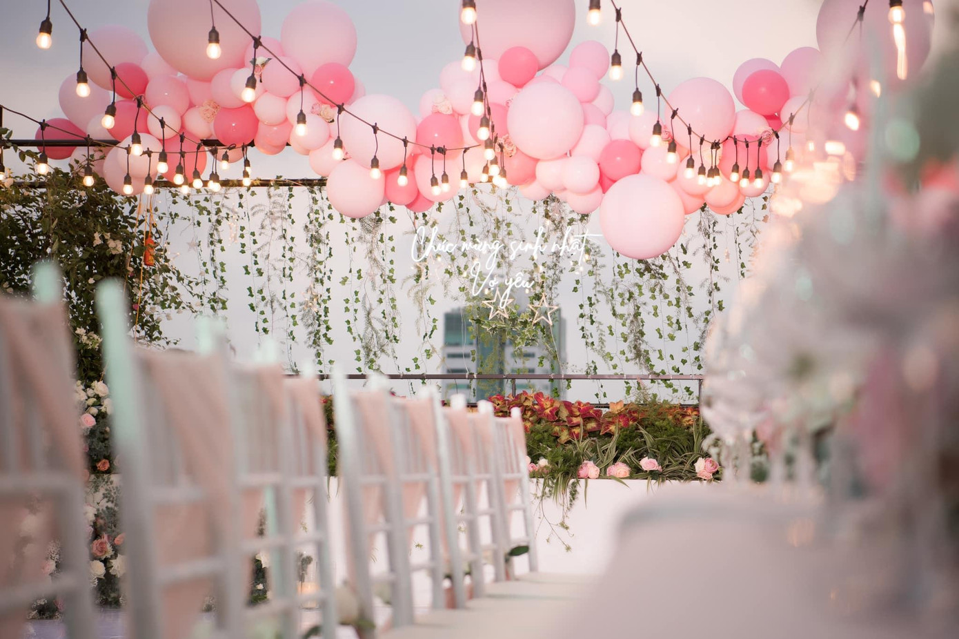 Buổi tiệc được trang trí với rất nhiều hoa tươi và bóng bay, được tổ chức ở trên tầng cao của một nhà hàng.