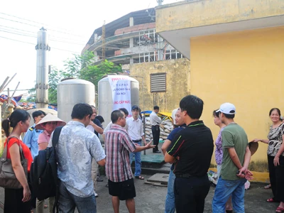 Người dân cùng Công ty Cổ phần đầu tư bất động sản Hà Nội lập biên bản và niêm phong mẫu nước tại trạm bơm để đưa đi xử lý. Ảnh: Tuấn Nguyễn