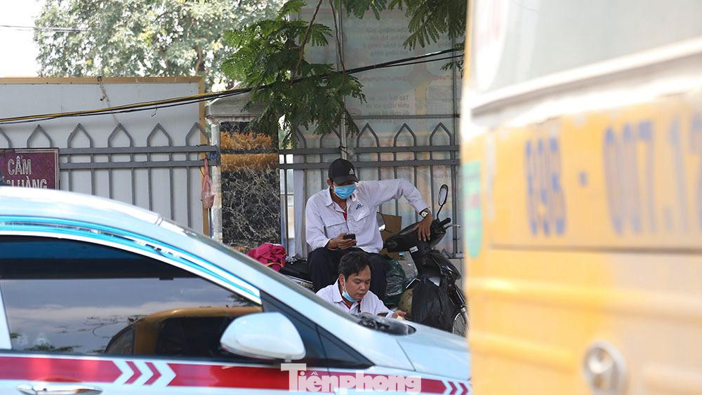 Nhiều tài xế taxi ngồi đành ngồi bấm điện thoại trong lúc chờ có khách tới.