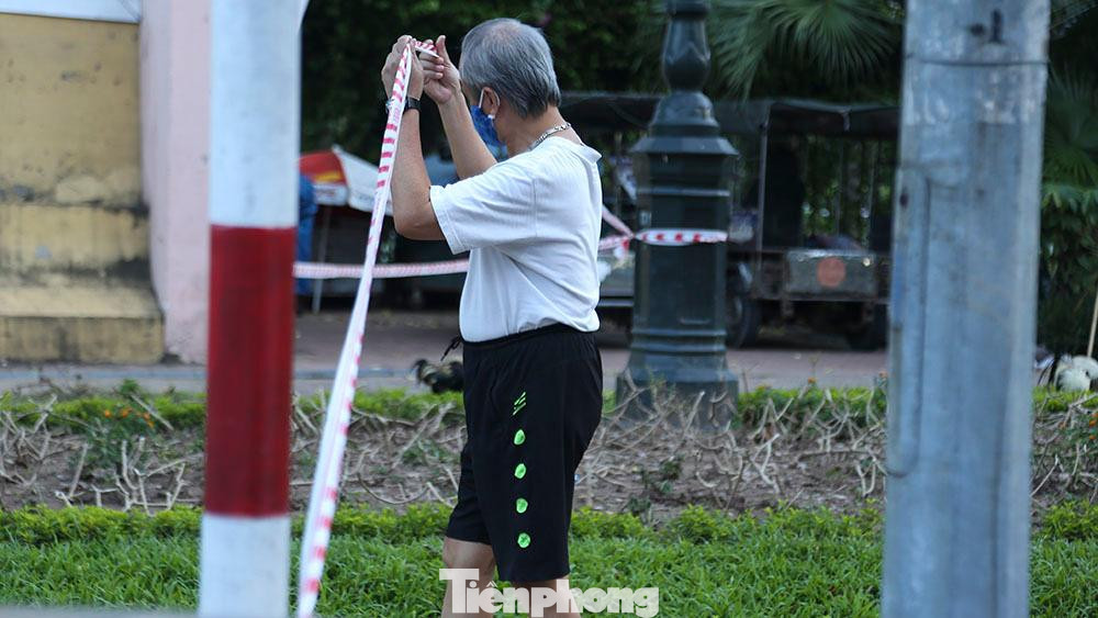 Tại công viên Thống Nhất, người dân vẫn vô tư kéo dây chắn để vào trong tập thể dục.