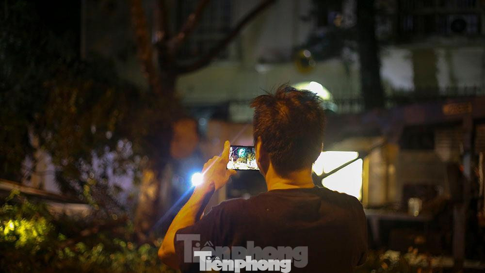 Mặc dù trời đã là 1 giờ sáng nhưng vẫn có rất nhiều người dân tò mò, quay lại cảnh công nhân cây xanh tiến hành cưa cây.