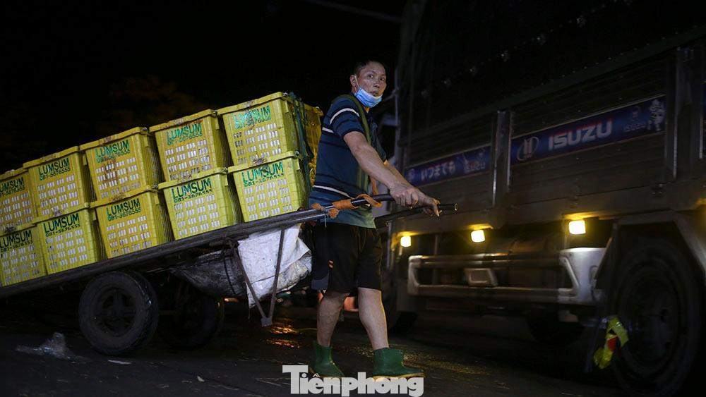 Những người làm nghề cửu vạn tại chợ nhanh chóng kéo hàng chục thùng rau, củ, quả từ điểm đỗ xe tải vào trong chợ.