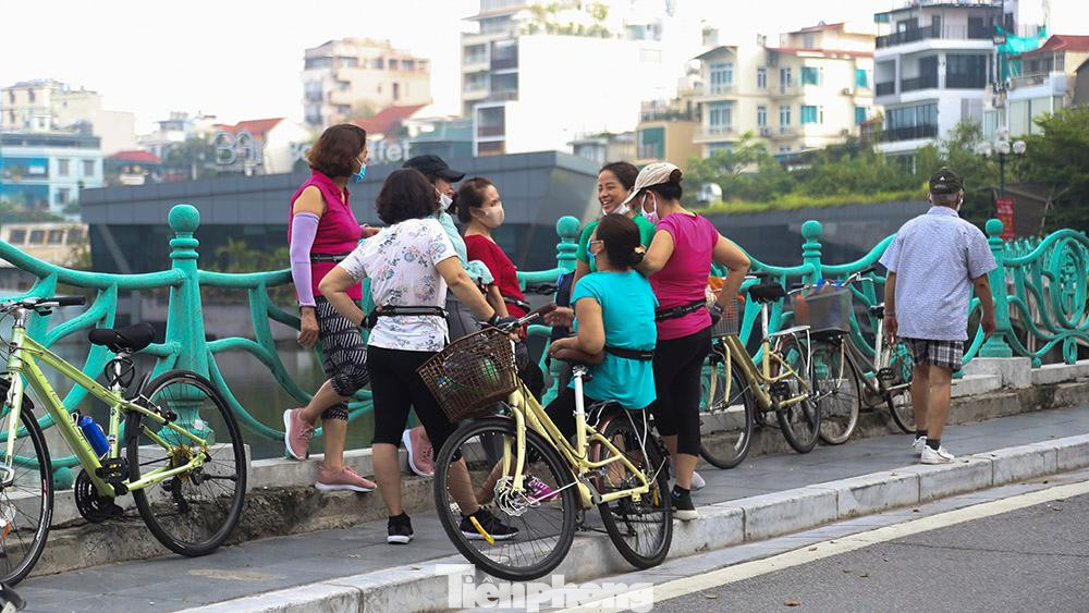 Sau khi tập thể dục, người dân tập trung ngồi nghỉ, hóng mát ven hồ; nhiều người vô tư bỏ khẩu trang ra để nói chuyện.