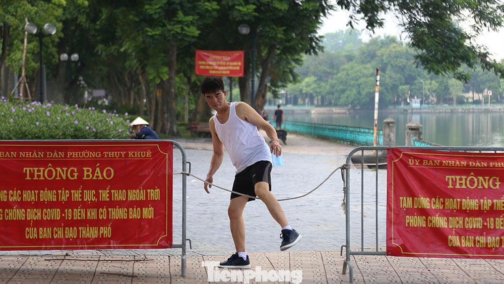 Người lớn, trẻ nhỏ đều chui qua dây chắn của lực lượng chức năng để vào khu vực vỉa hè của công viên tập thể dục