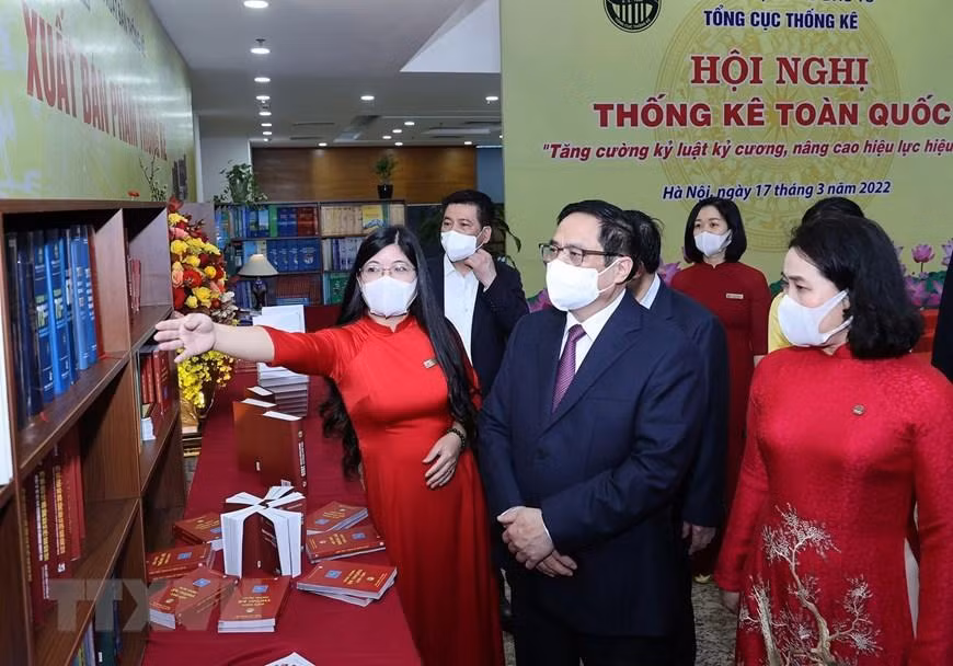 Nhân viên ngành thống kê giới thiệu với Thủ tướng Phạm Minh Chính về sách, hình ảnh, hiện vật của ngành thống kê. (Ảnh: Dương Giang/TTXVN)