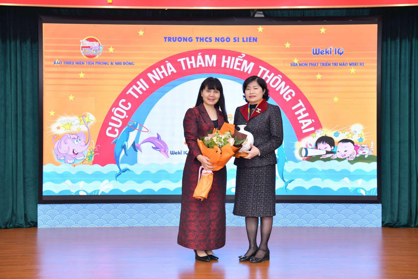 Nhà báo Trần Lan Phương (bìa trái) - Phó Tổng Biên tập báo Thiếu niên Tiền phong và Nhi đồng tặng hoa cảm ơn nhà giáo Phạm Thu Hà - Bí thư Chi bộ, Hiệu trưởng nhà trường và bà Bùi Thị Phượng - Đại diện nhãn hàng sữa non Weki IQ. Ảnh: Trường Phạm