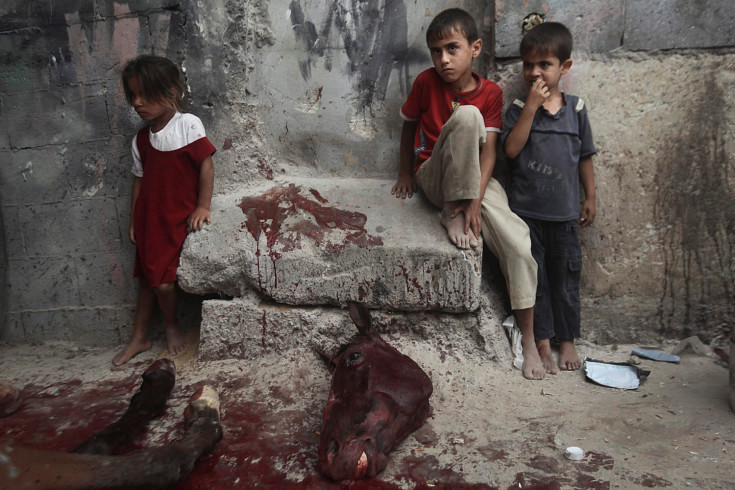 Trẻ em Palestine đứng bên cạnh xác con ngựa bị giết thịt trong một khu phố nghèo ở Dải Gaza