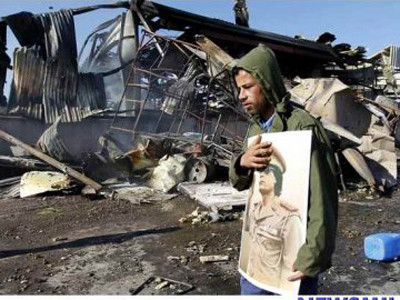 Một người dân ôm ảnh Đại tá Gadhafi bên đống đổ nát Ảnh: Newsmild