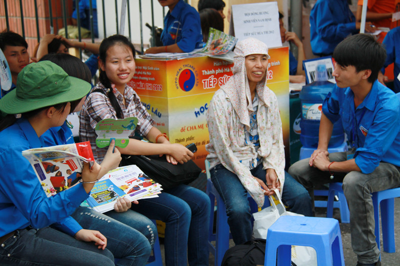 Hai mẹ con thí sinh ngồi trò chuyện với các sinh viên tình nguyện. Ảnh: Trường Phong