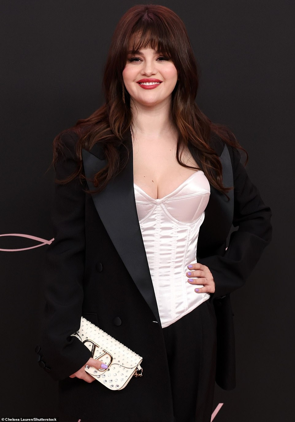 Vóc dáng của Selena có thể không mảnh mai bằng Nicola và Victoria nhưng sự gợi cảm chắc chắn lấn át. Chiếc áo trắng dáng corset giúp nữ ca sĩ sinh năm 1992 khoe vòng một. Áo vest phom rộng, cùng quần baggy không chỉ che được khuyết điểm hình thể, còn làm tăng sự thanh lịch. Trang điểm mắt khói kết hợp màu son môi đỏ thực sự nâng tầm nhan sắc cho Selena. Ảnh: Shutterstock.