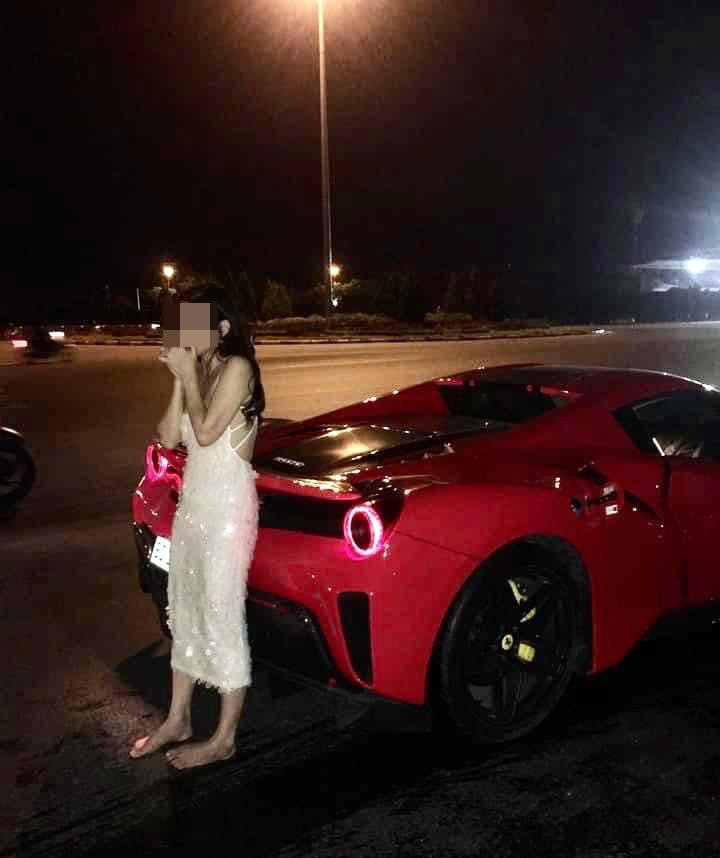 Cô gái mặc váy trắng đứng bên cạnh xe Ferrari.