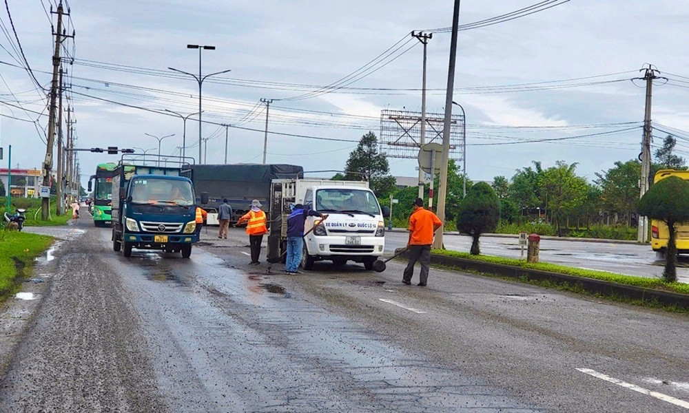 Hình ảnh đội công nhân vá quốc lộ lúc mặt đường ướt sũng.