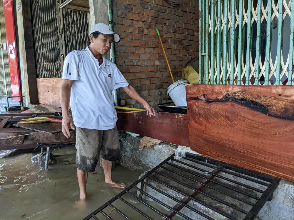 Ông Nguyễn Tập (trú ở thị trấn Chợ Chùa) dùng những thanh gỗ chắn tạm trước nhà để ngăn sóng nước tràn vào. “Nhiều xe chạy nhanh quá, sóng mạnh tràn cả vào nhà”, ông Tập nói.