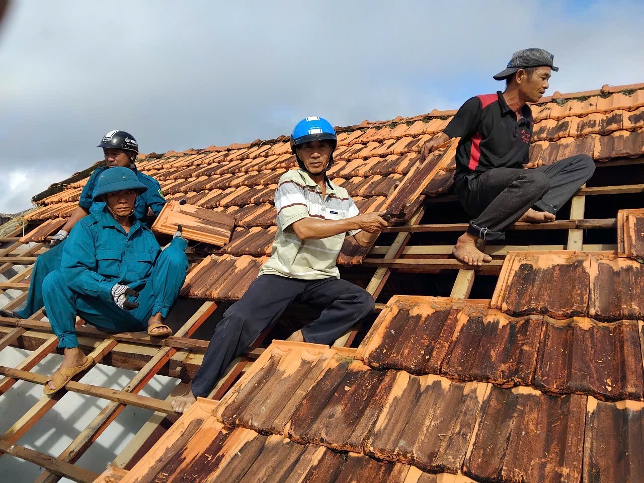 Lực lượng công an, dân quân và đoàn viên thanh niên hỗ trợ người dân lợp lại mái nhà.