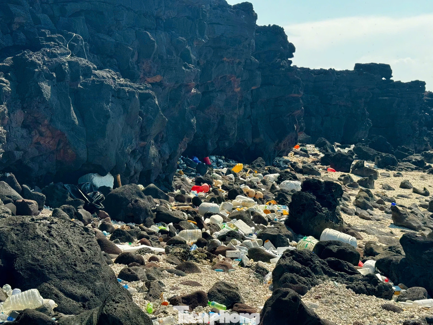 Lẩn khuất trong những vách đá nham thạch, lùm cây là những hàng trăm chai nhựa, thùng xốp, túi nilon, giày dép… đang ngày ngày bủa vây lấy đảo. Ảnh: Nguyễn Ngọc.