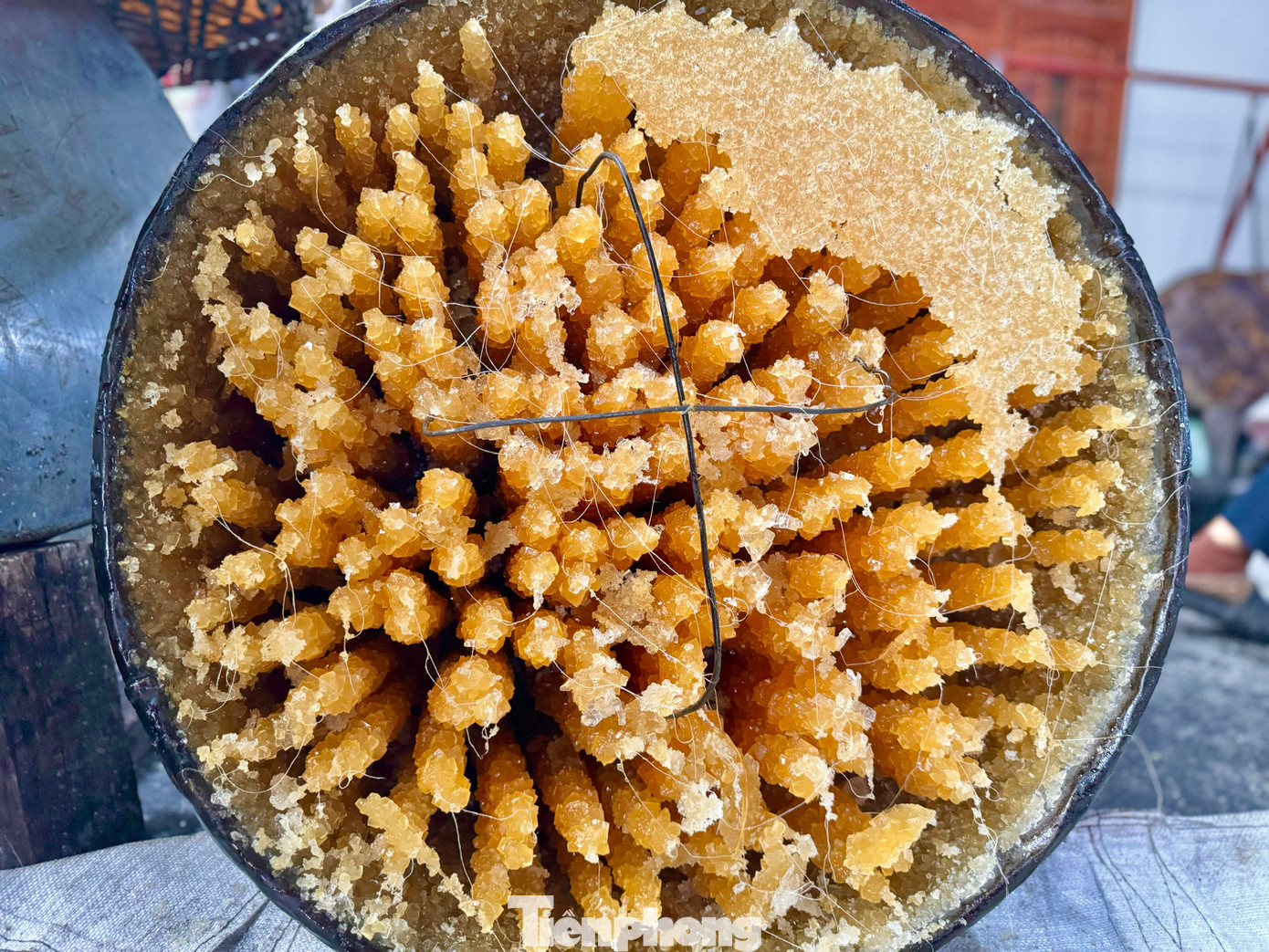 Bà Nguyễn Thị Lắm (70 tuổi, vợ ông Chính) cho hay dùng cách thử đường bằng nước chính xác hơn. Nhỏ nước đường đang sôi vào đĩa nước lạnh nếu các giọt đường kết dính với nhau là đường đã tới, còn giọt đường tan ra là phải nấu thêm. Ảnh: Nguyễn Ngọc