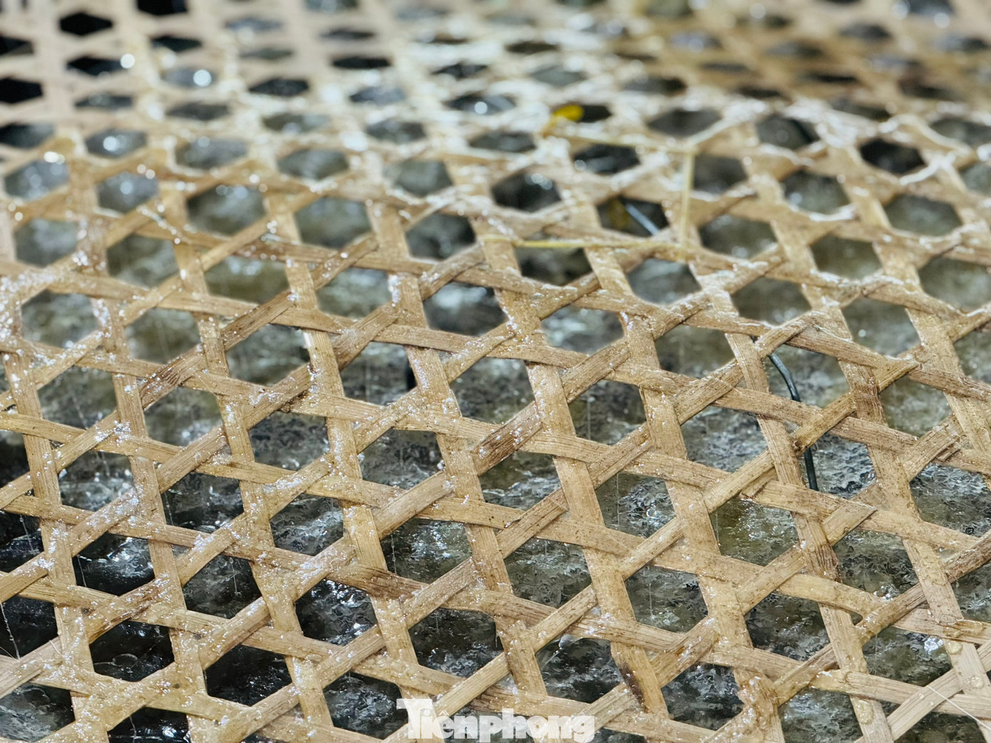 “Để đường kết tinh đều, đẹp cần 2 bí quyết là dùng vỉ chỉ và yếu tố tĩnh. Vỉ chỉ là 2 vỉ tre được cố định bởi khung sắt, chỉ được luồn qua vỉ tre sau đó bỏ vào thùng sắt rồi đổ nước đường vào thùng. Vỉ chỉ sẽ giúp đường phèn kết tinh và bám vào thành từng mảng như đá thạch anh. Bí quyết thứ hai là thùng chứa nước đường phải đặt ở nơi bằng phẳng. Suốt quá trình chờ đường kết tinh không được làm thùng rung động”, bà Lắm nói. Ảnh: Nguyễn Ngọc