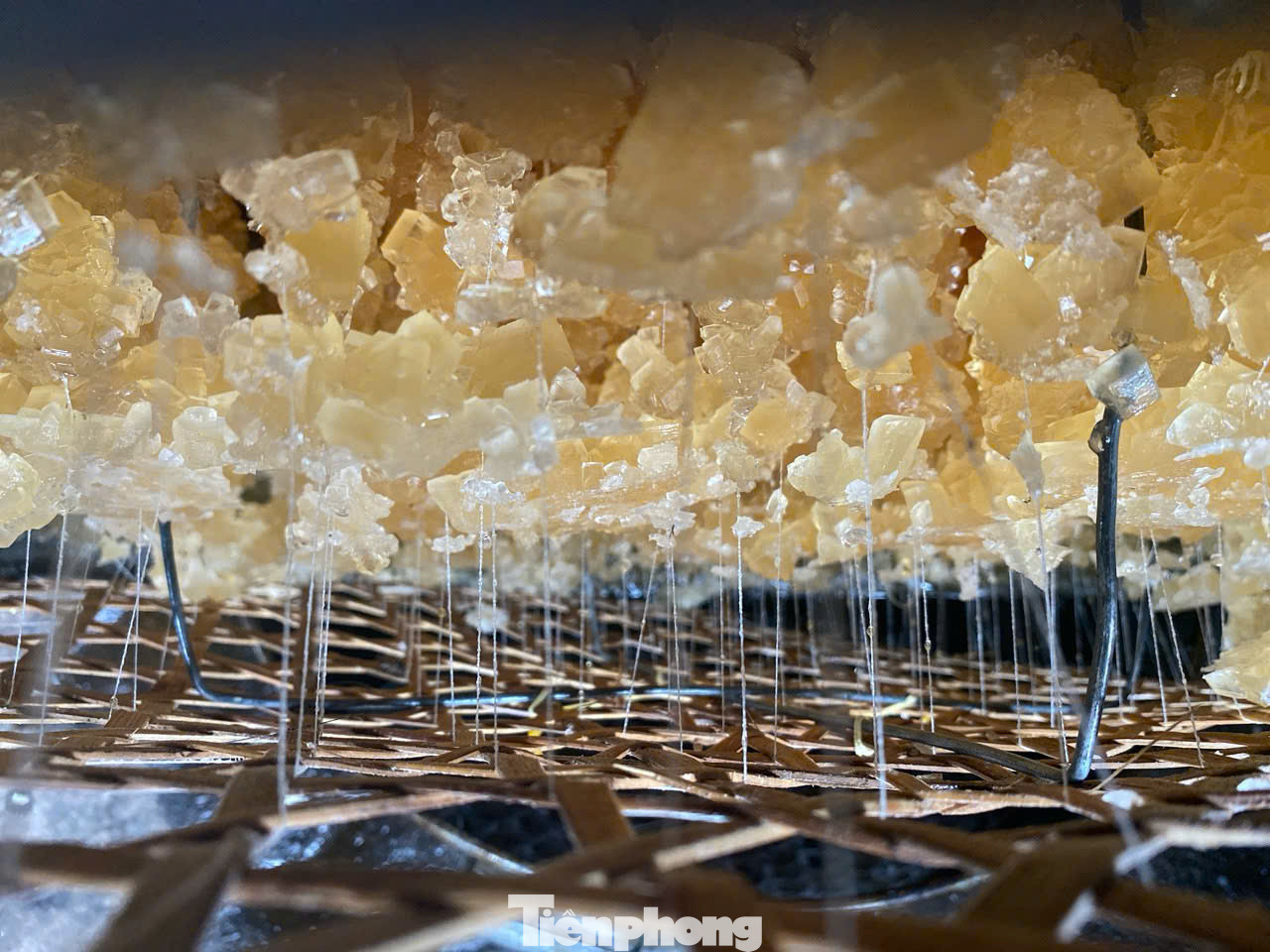 “Để đường kết tinh đều, đẹp cần 2 bí quyết là dùng vỉ chỉ và yếu tố tĩnh. Vỉ chỉ là 2 vỉ tre được cố định bởi khung sắt, chỉ được luồn qua vỉ tre sau đó bỏ vào thùng sắt rồi đổ nước đường vào thùng. Vỉ chỉ sẽ giúp đường phèn kết tinh và bám vào thành từng mảng như đá thạch anh. Bí quyết thứ hai là thùng chứa nước đường phải đặt ở nơi bằng phẳng. Suốt quá trình chờ đường kết tinh không được làm thùng rung động”, bà Lắm nói. Ảnh: Nguyễn Ngọc