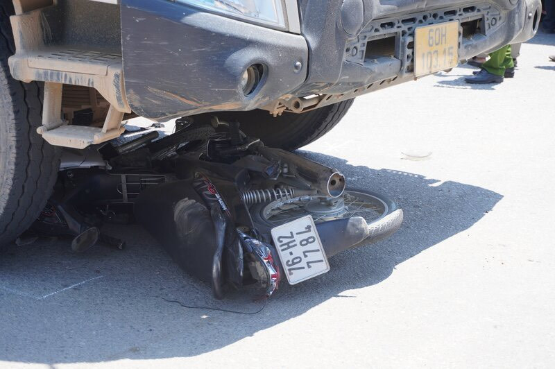 Chiếc xe máy của nạn nhân bị kẹt dưới gầm xe tải.