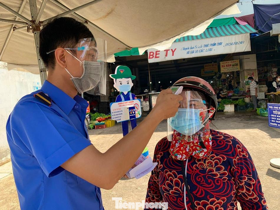 Đo thân nhiệt và kiểm tra phiếu trước khi vào chợ Quảng Ngãi. Ảnh: Nguyễn Ngọc