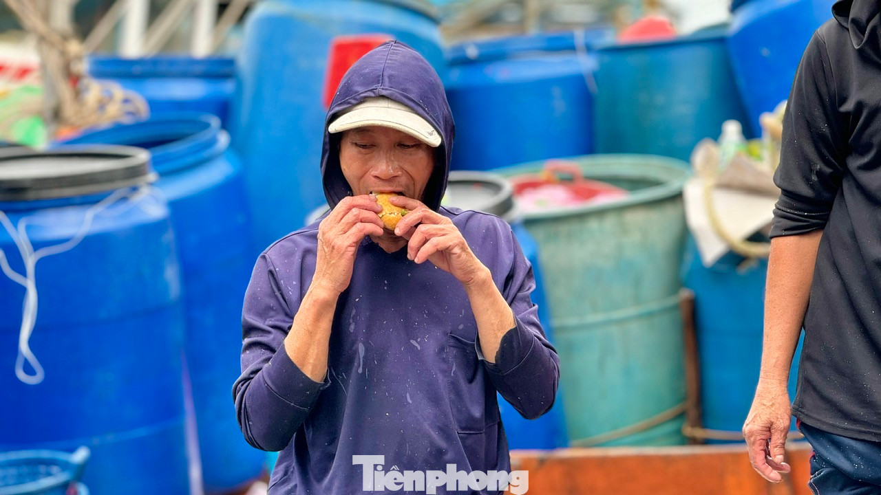Ngư dân ăn vội ổ bánh mì để tiếp tục công việc. Ảnh: Nguyễn Ngọc