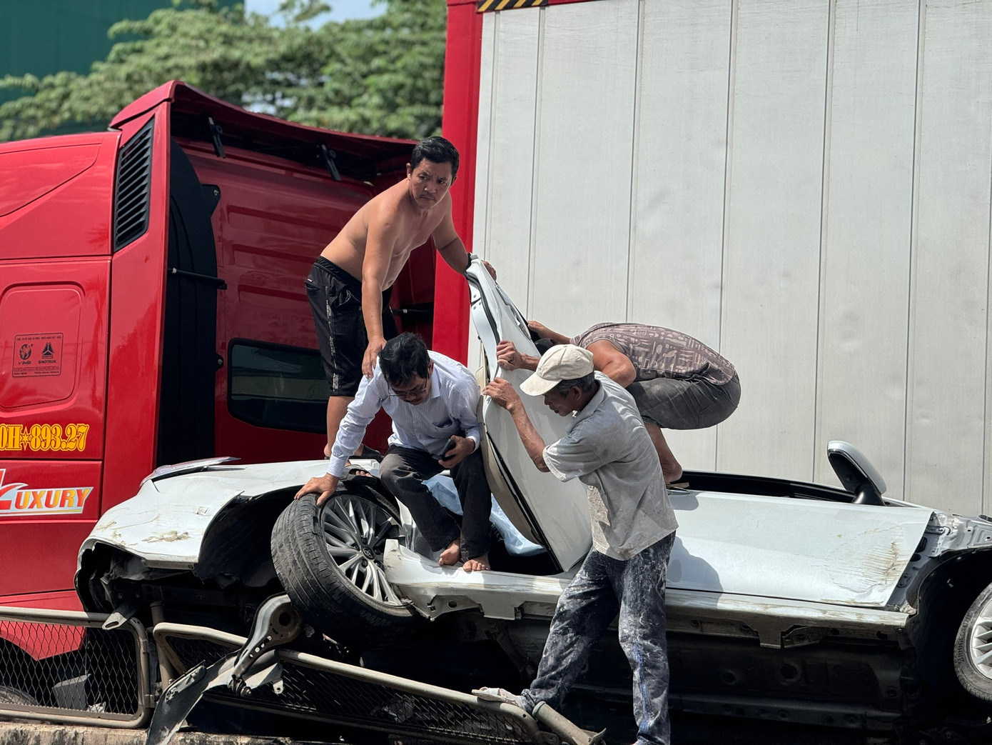 Người dân hỗ trợ các nạn nhân bên trong xe ô tô con ra ngoài. Ảnh: Nguyễn Ngọc Người dân hỗ trợ các nạn nhân bên trong xe ô tô con ra ngoài. Ảnh: Nguyễn Ngọc