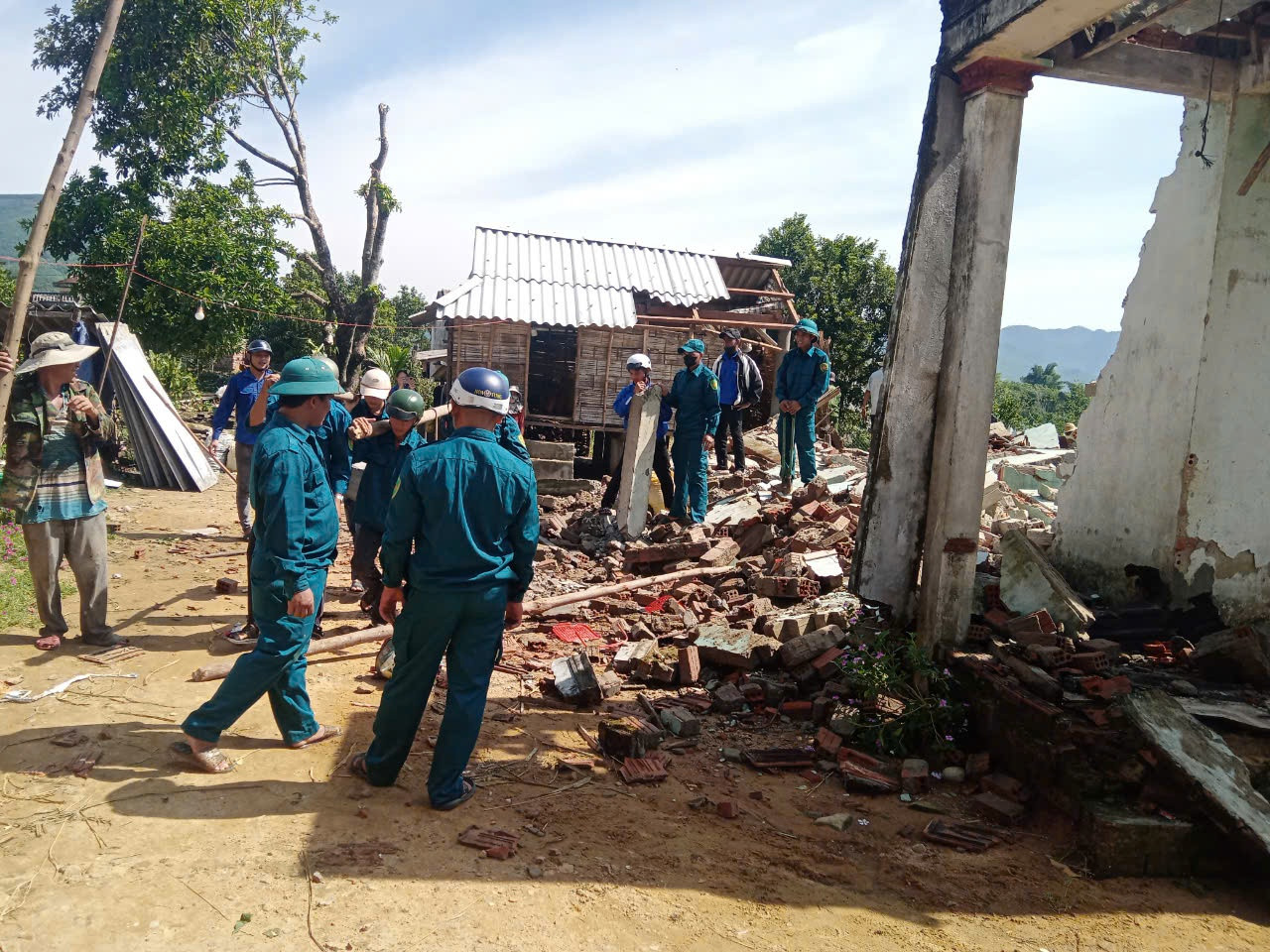 Lực lượng dân quân cùng đoàn viên, thanh niên dọn dẹp nhà giúp bà Đinh Thị Đòa.