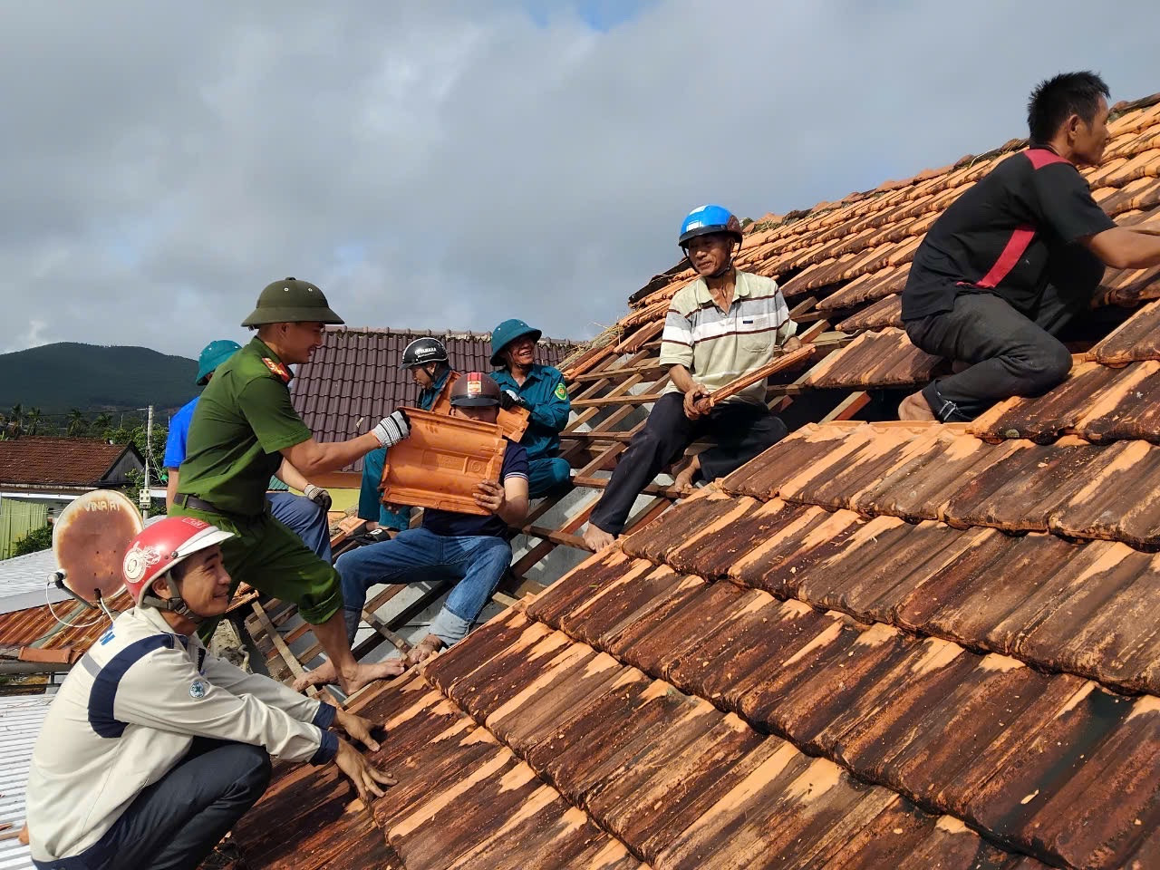 Lực lượng công an, dân quân và đoàn viên thanh niên hỗ trợ người dân lợp lại mái nhà.