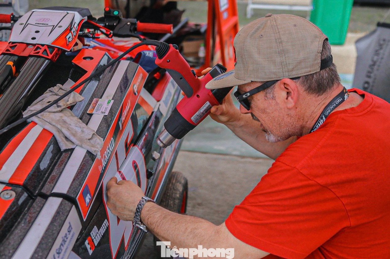 Một thành viên của một đội đua kỹ càng dán những logo, biểu tượng của đội mình lên chiếc mô tô yêu thích. Với các vận động viên những chiếc mô tô là "con cưng" nên được chăm sóc rất kỹ càng.