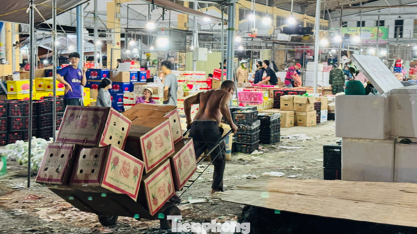 Họ bốc vác, vận chuyển cả trăm tấn hàng đi đến các ki-ốt trong chợ và đưa lên các xe tải nhỏ mang đi khắp nơi trong và ngoài tỉnh phục vụ nhu cầu mua sắm Tết của người dân. Ảnh: Nguyễn Ngọc