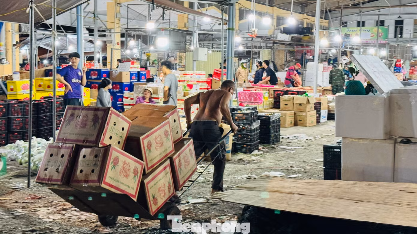 Họ bốc vác, vận chuyển cả trăm tấn hàng đi đến các ki-ốt trong chợ và đưa lên các xe tải nhỏ mang đi khắp nơi trong và ngoài tỉnh phục vụ nhu cầu mua sắm Tết của người dân. Ảnh: Nguyễn Ngọc