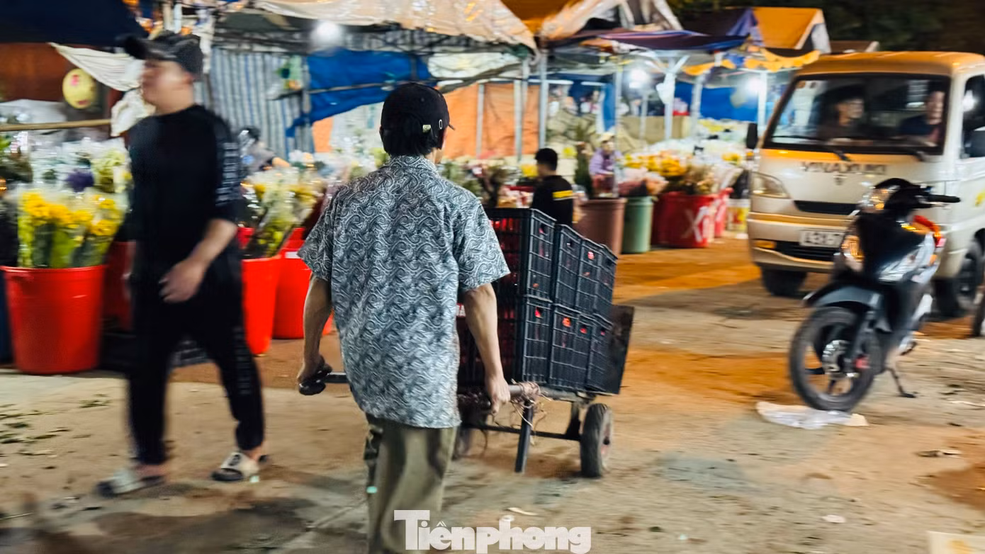 “Những ngày gần Tết, lượng hàng hóa về nhiều nên anh em làm nghề bốc vác ở chợ đầu mối phải làm việc liên tục và không màng tới giờ ngủ, khi nào hết hàng thì nghỉ. Mệt thì rất mệt nhưng bù lại có tiền để lo cho con cái có được một cái Tết ấm thì vất vả mấy cũng phải cố. Hôm nào chúng tôi cũng làm việc từ 21h cho đến 7h sáng hôm sau”, ông Phú nói. Ảnh: Nguyễn Ngọc