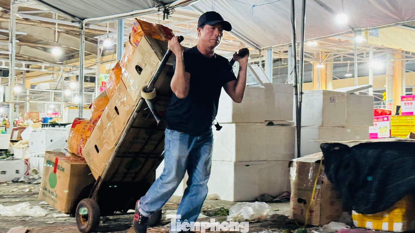 “Mỗi thùng hàng kéo từ xe vào quầy của tiểu thương được trả công 2.000 đồng. Một chuyến thường chất 10 thùng. Mỗi người thường kéo 300 - 400 thùng trong đêm, kiếm khoảng 800.000 đồng. Dịp Tết, dù công việc vất vả, kéo dài nhưng với mong muốn kiếm thêm thu nhập để trang trải cho cái Tết nên mệt mấy cũng phải làm”, anh Anh thổ lộ. Ảnh: Nguyễn Ngọc