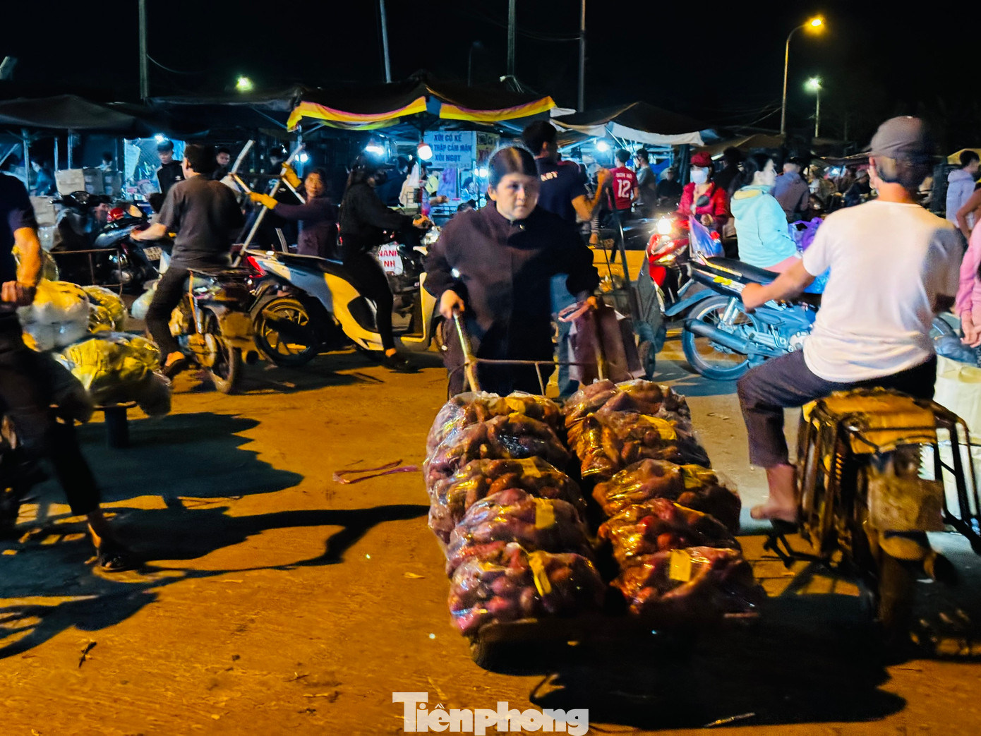 Không chỉ có “cửu vạn” là nam giới, nhiều người phụ nữ cũng làm công việc nặng nhọc này. Quan sát khắp các ngã chợ, không khó để bắt gặp hình ảnh những người phụ nữ tuổi chừng 40-50 cũng miệt mài công việc bốc hàng thuê. Họ thoăn thoắt bốc hàng vào xe rồi kéo đi. Ảnh: Nguyễn Ngọc