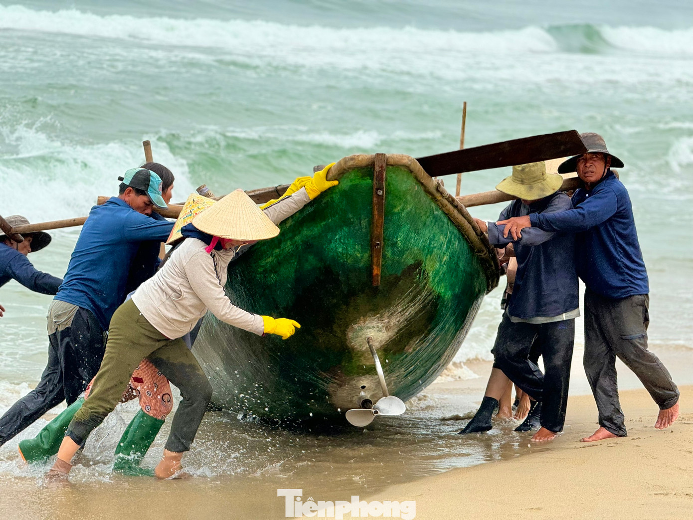 Ngay khi thuyền vừa cập bờ, những người vợ của ngư dân cũng khẩn trương ra hỗ trợ chồng con đưa chiếc thuyền vào sâu trong bờ để tránh những con sóng lớn.