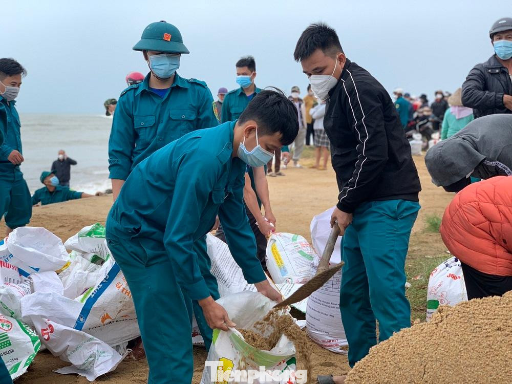 Theo ghi nhận của PV, triều cường, kèm theo sóng lớn đổ xô vào bờ đã làm cho hơn 200 mét bờ biển thuộc khu dân cư số 1, thôn Phổ Trường, xã Nghĩa An, TP Quảng Ngãi bị sạt lở nghiêm trọng. Sóng biển hiện đã ăn sâu vào gần sát nhà dân đang ở. Tuyến đường bê tông chạy dọc bờ biển nhiều vị trí bị sóng lớn đánh khoét sâu vào lòng đường, tạo thành những hàm ếch lớn. Hiện chính quyền địa phương đã vận động người dân ở khu vực nguy hiểm di dời đến nhà người thân ở xen ghép để đảm bảo an toàn tính mạng và tài sản. Trong ảnh: Lực lượng chức năng tiến hành xúc cát gia cố bờ biển.