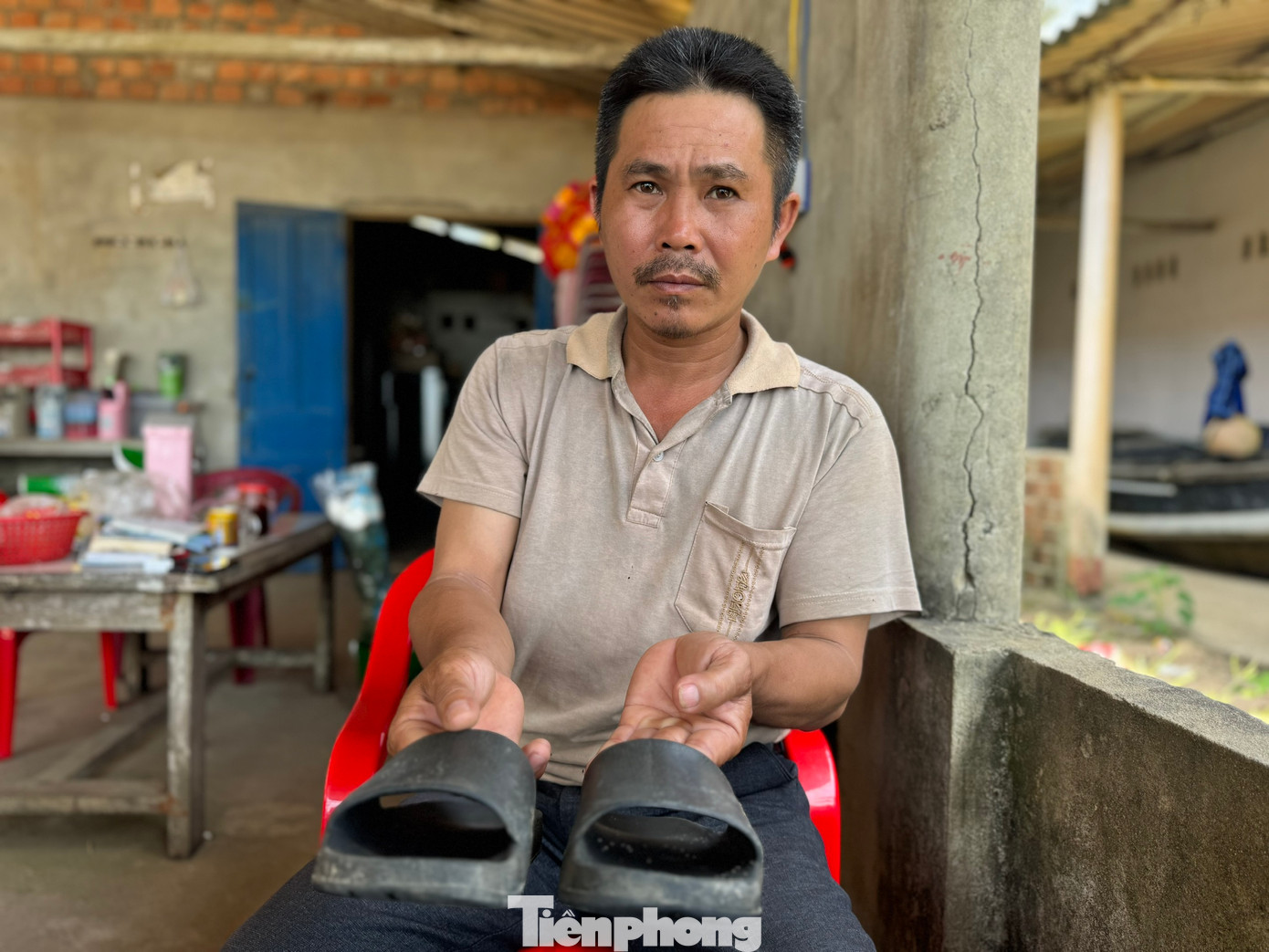 Đỗ Thành Thân bên đôi dép của con bỏ lại trên bờ biển.