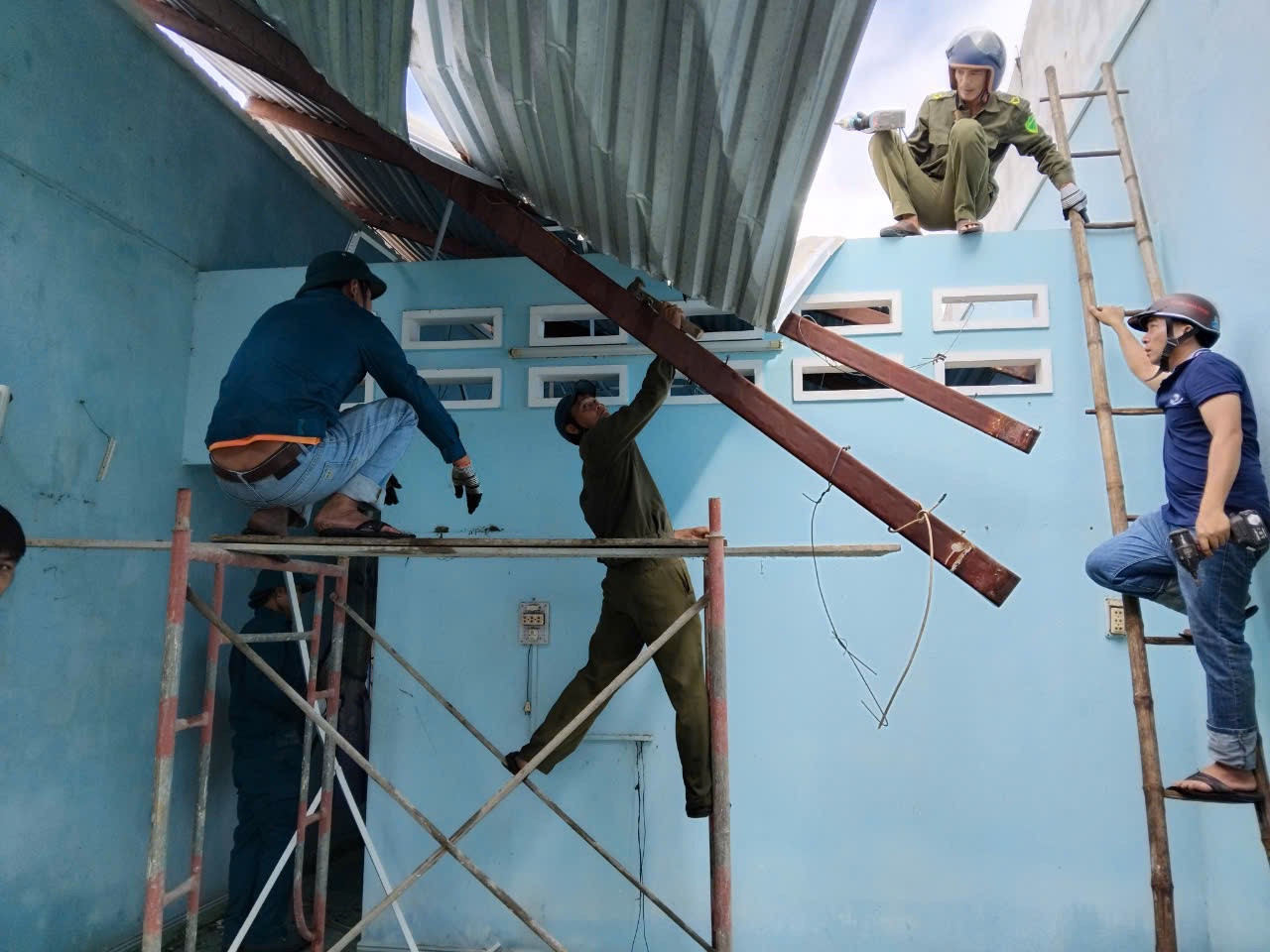 Lực lượng công an, dân quân và đoàn viên thanh niên hỗ trợ người dân lợp lại mái nhà.