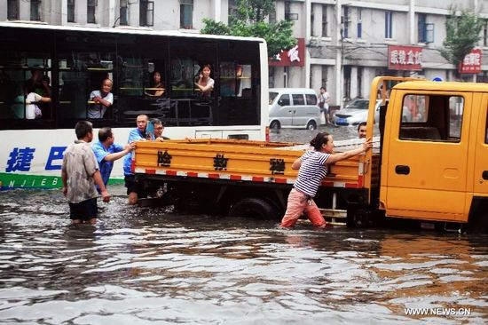 Mọi người di chuyển một chiếc xe ra khỏi đoạn đường ngập nước ở quận Thiết Tây, Thẩm Dương, thủ phủ tỉnh Liêu Ninh, đông bắc Trung Quốc, ngày 16/8/2013. Ảnh: Tân Hoa Xã 