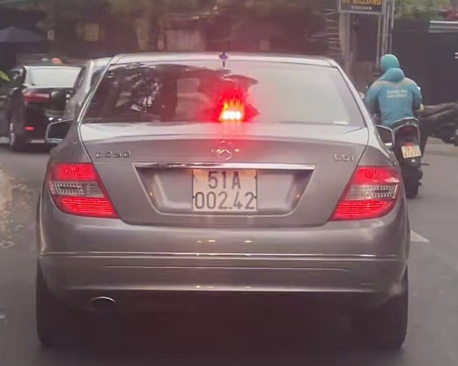 Ô tô hiệu Mercedes biển trắng bật đèn xanh đỏ.