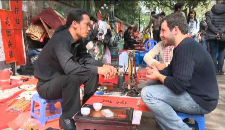 Adi (phải) làm ông đồ tại Văn Miếu. Ảnh: Lê Ngọc