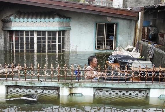 Một người dân vận chuyển đồ đạc trong cảnh nước ngập ngang ngực trước nhà mình ở thị xã Dampalit, thành phố Malabon, phía bắc Manila