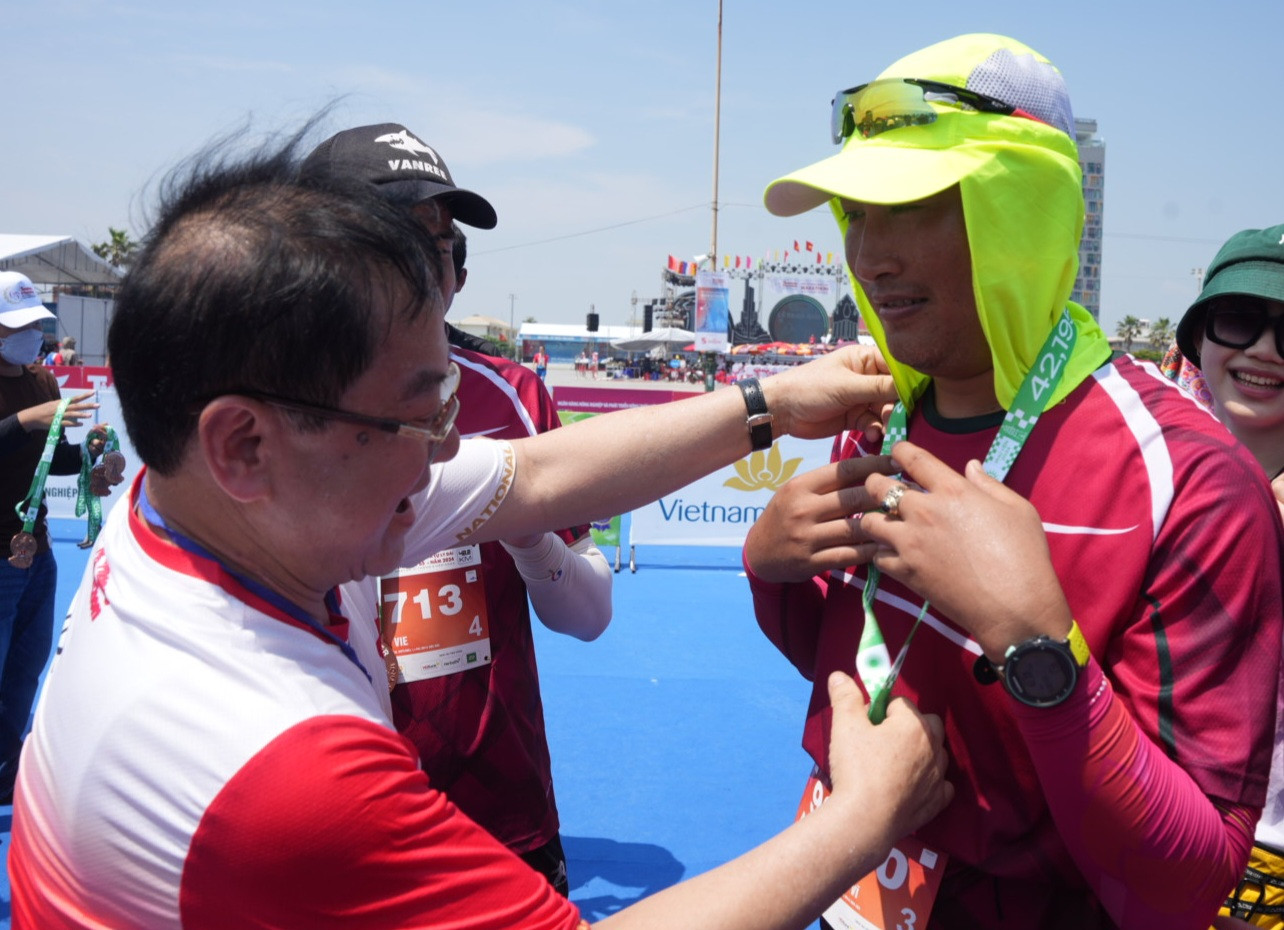 Nhà báo Lê Xuân Sơn - Tổng Biên tập báo Tiền Phong, đồng Trưởng Ban tổ chức Tiền Phong Marathon 2024, trao huy chương tặng vận động viên ở vạch đích.